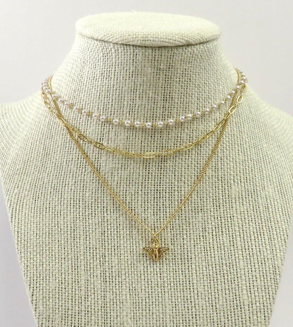 Beautiful gold and pearl 3 layer necklaces with bee pendant on a necklace mannequin and white background