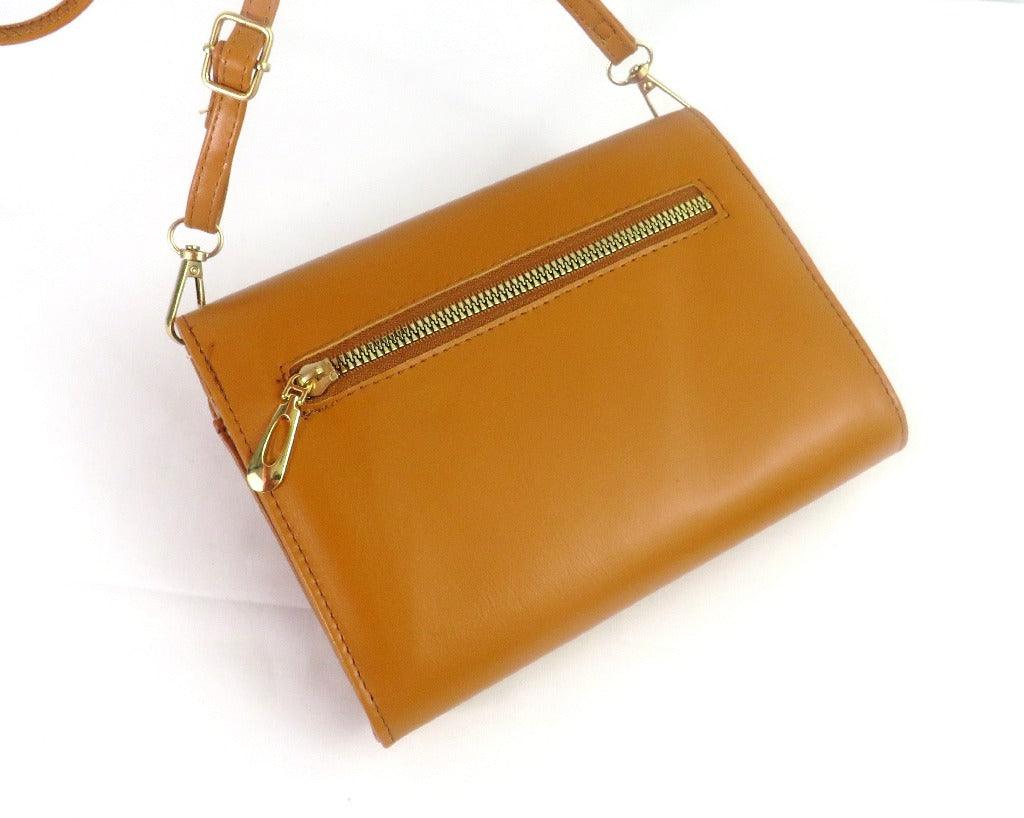 The back of the camel crossbody bag showing the zipper detail and the strap details on a white background