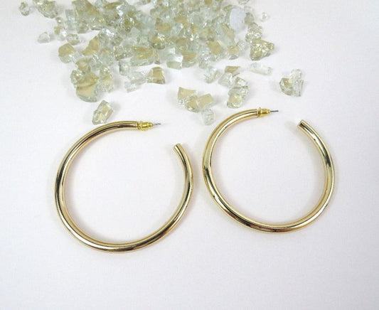 Everyday large gold hoops laying on a white background with clear crystals pieces