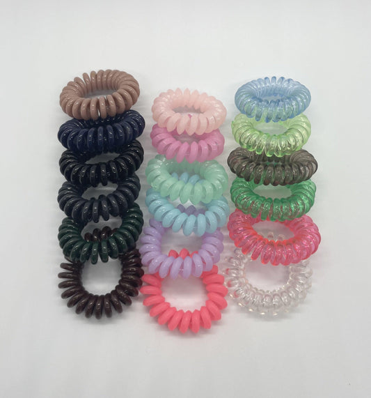 18 spiral hair ties of various colors on a white background