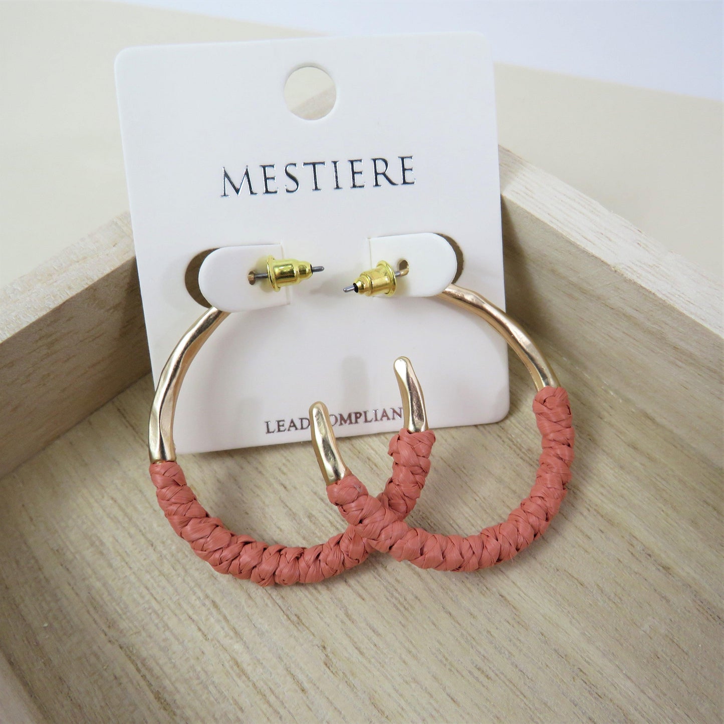 Coral and gold rattan wrapped hoops on a wood backround