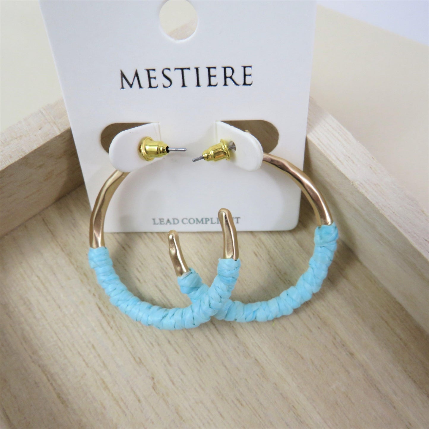 Teal and gold rattan wrapped hoops on a wood background