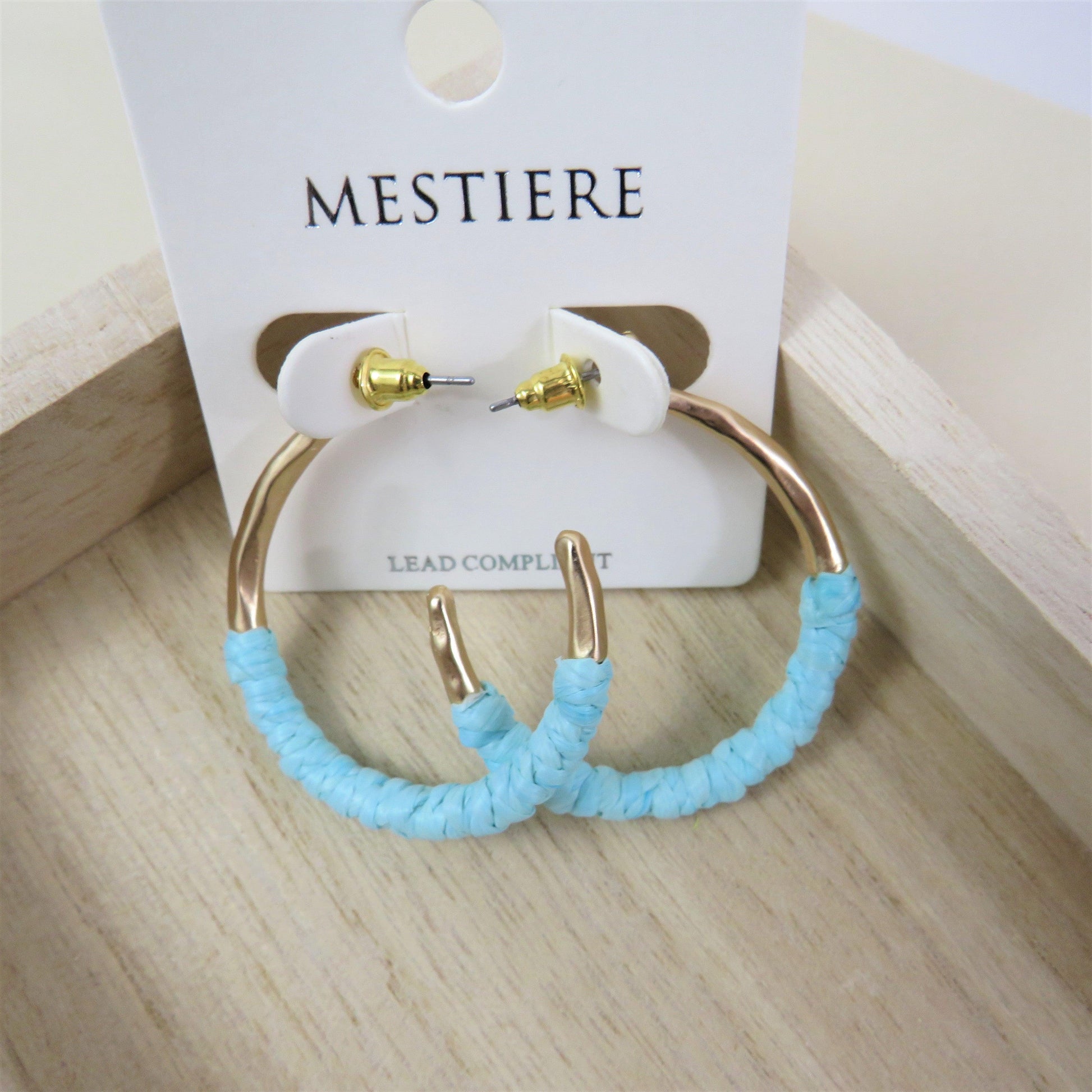Teal and gold rattan wrapped hoops on a wood background
