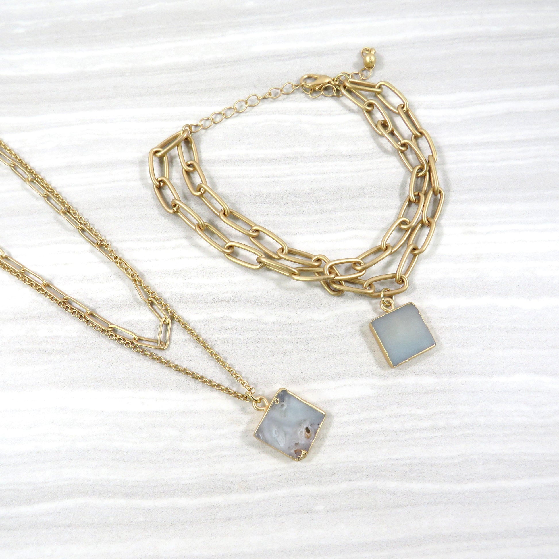 double layer gold chain necklace and bracelet set with a Amazonite stone on a gray and white tile background