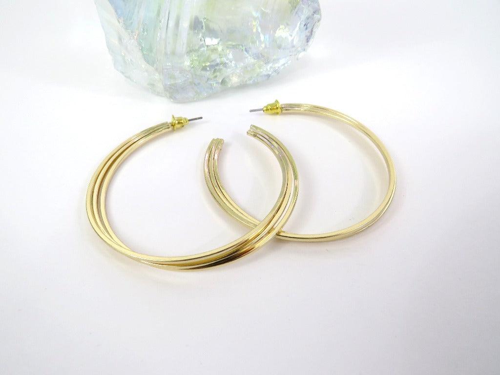 gold layered hoop with post backs on a white background next to a clear crystal